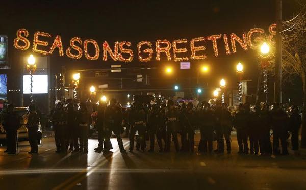 Police and riot squads stand under a "Seasons Greetings" sign in Ferguson, MO, Monday night. (Reuters)